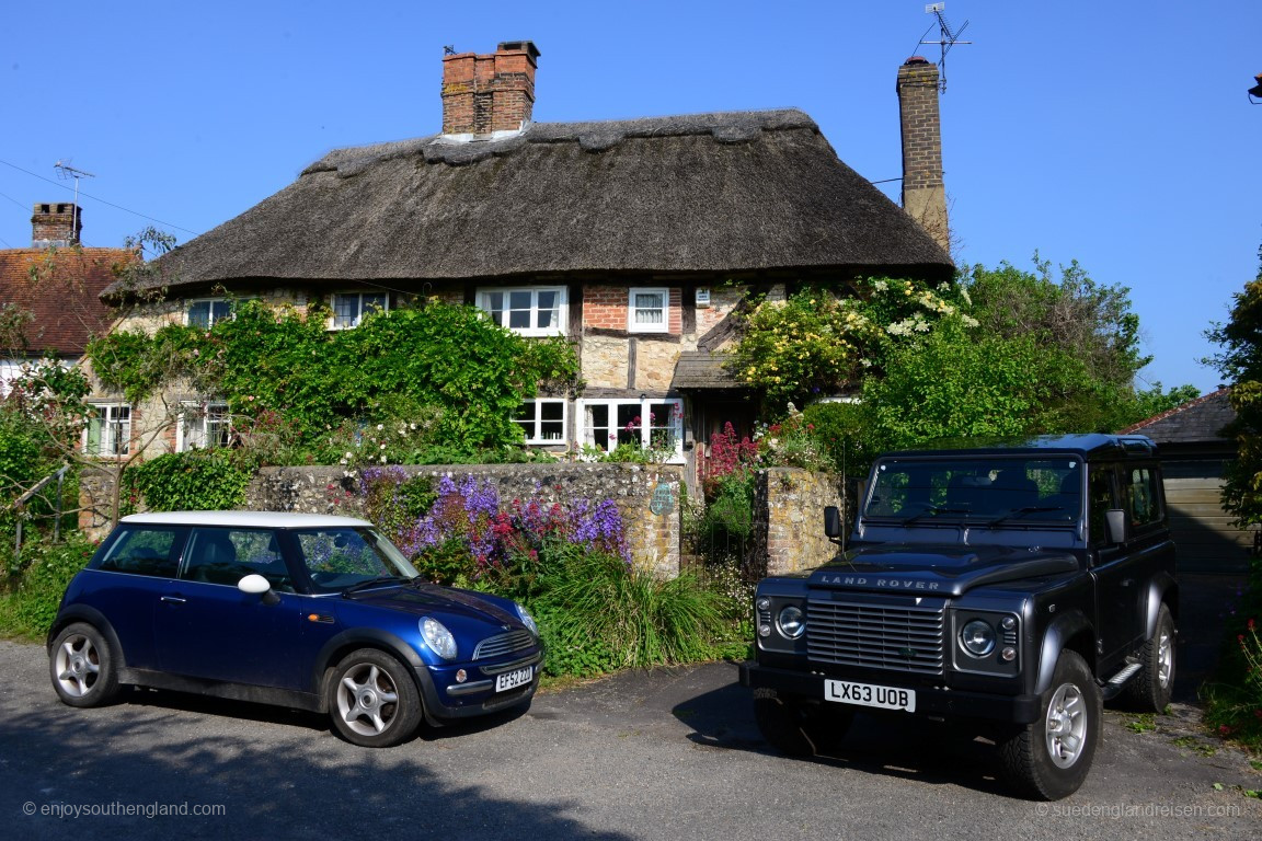 Klassischer geht es kaum: Ein traditionelles südengliches thatched Haus in Amberley mit zwei (ursprünglich) britischen Autos davor!