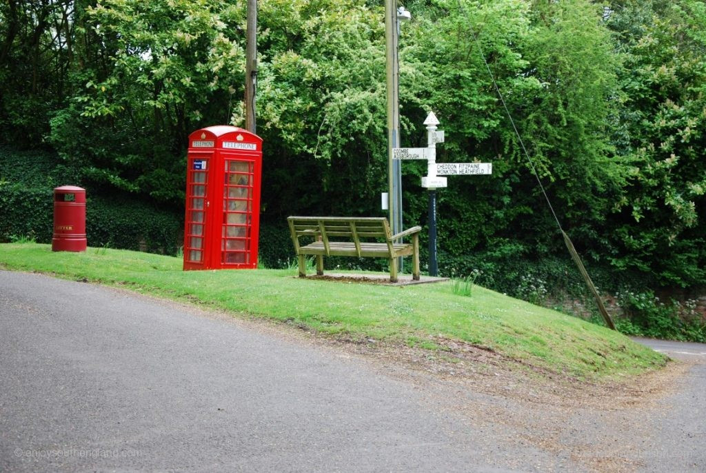 A very typical crossroads in nowhere: Pillarbox, telephone booth, bank and signpost.